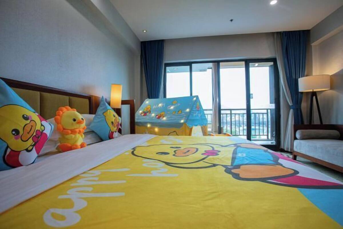 Habitación de hotel con una cama decorada con personajes de dibujos animados, un balcón con vistas y un ventanal grande.