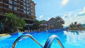 Une piscine d’hôtel avec une eau d’un bleu limpide, des palmiers et un bâtiment doté de balcons.