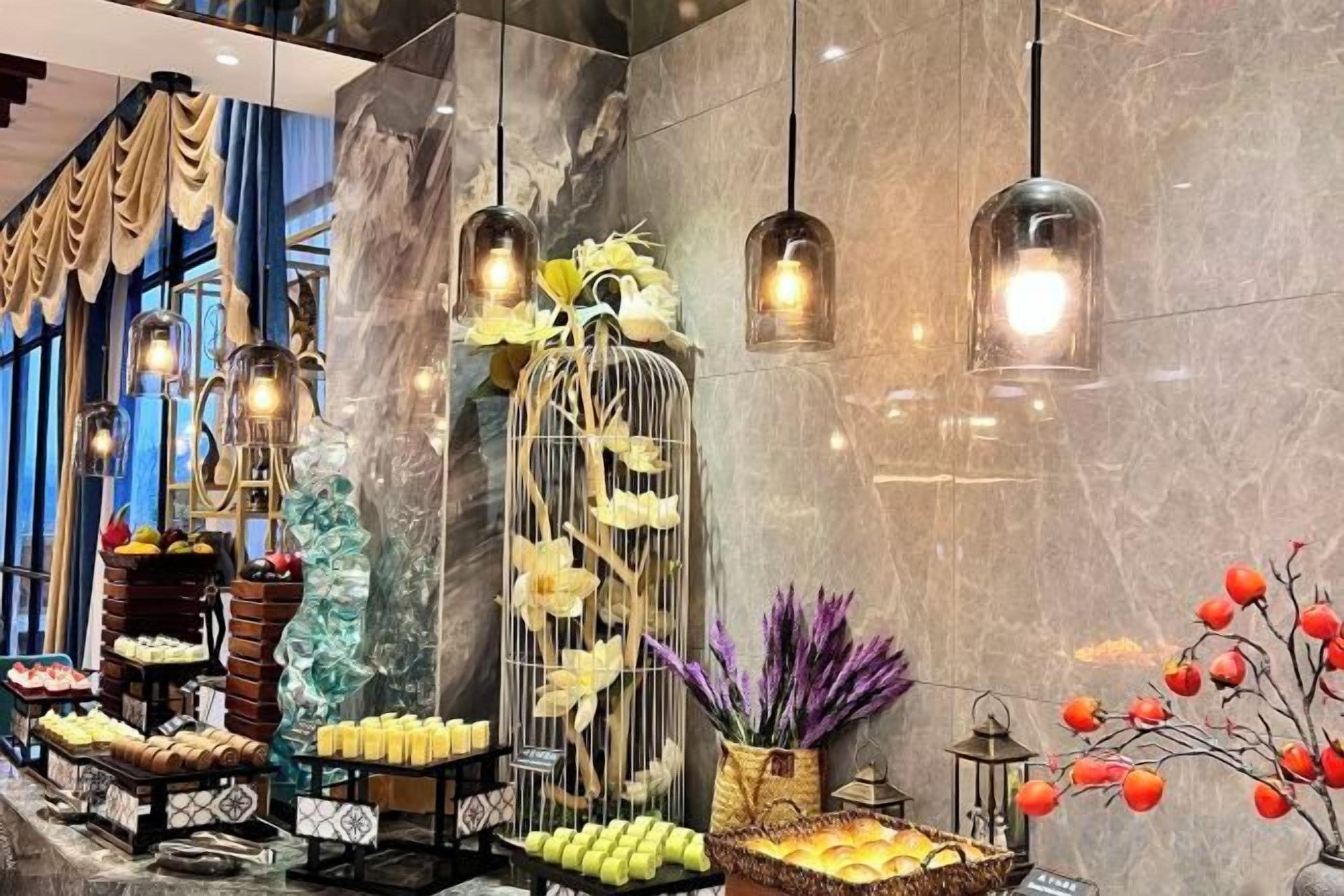 A hotel lobby with a marble wall, decorative lighting, and various floral arrangements.