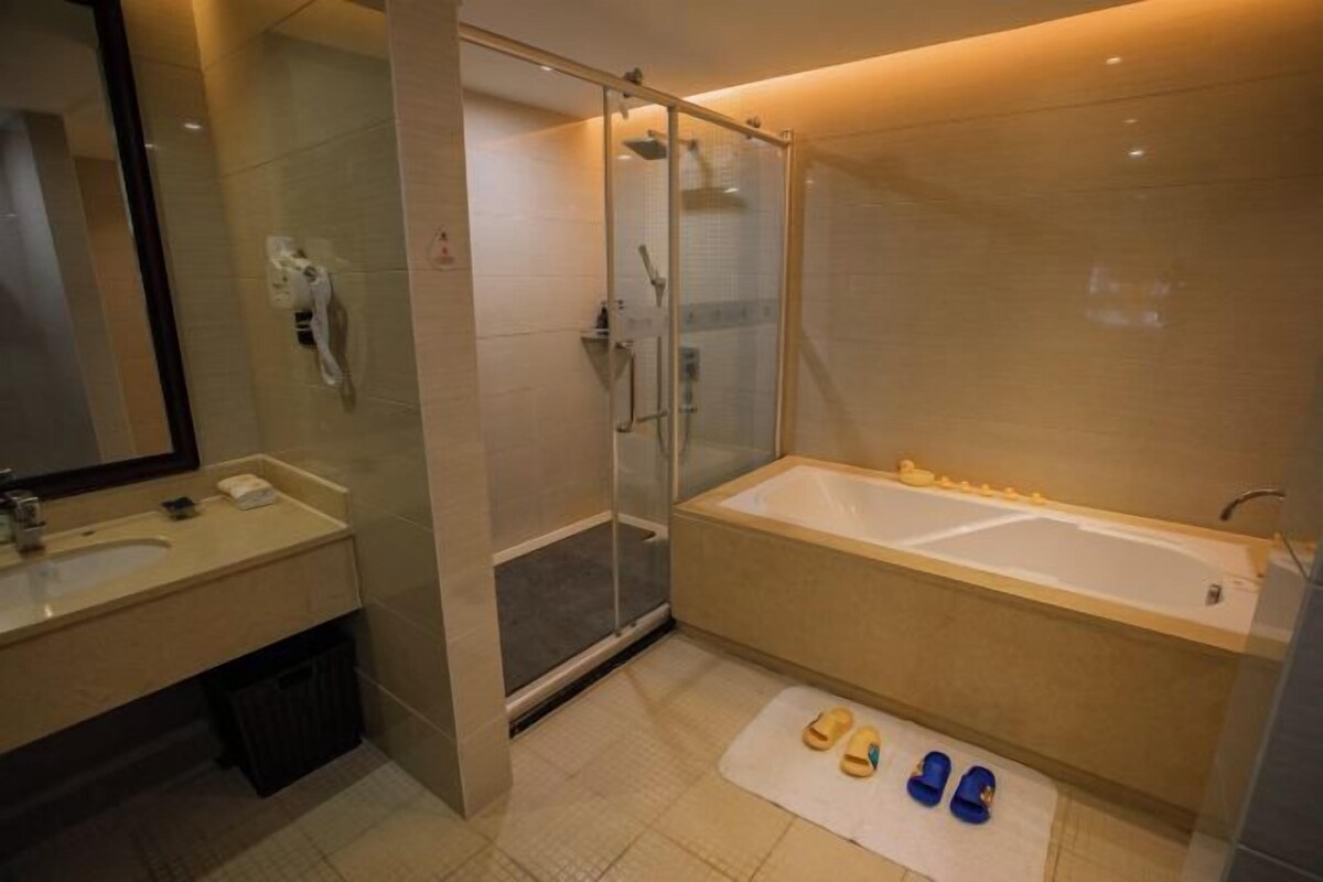 A modern bathroom with a glass-enclosed shower, a bathtub, and a large mirror.