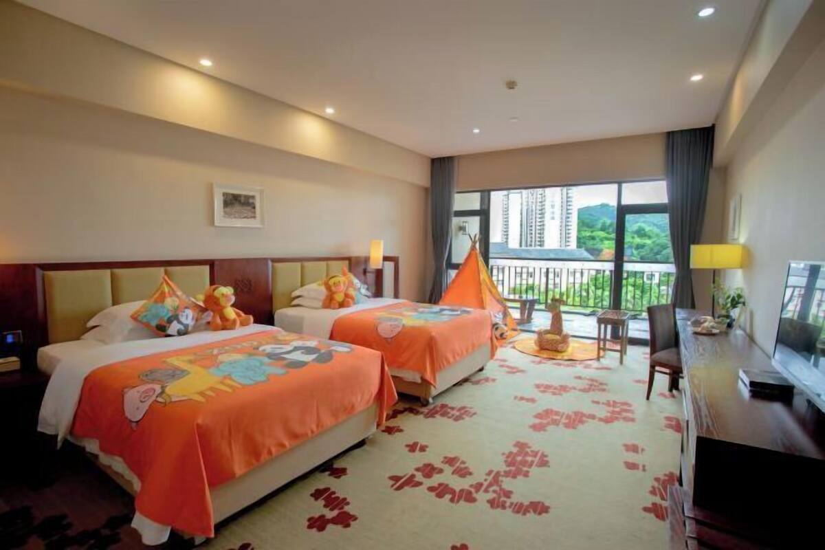Habitación de hotel con dos camas, un escritorio, una silla, un televisor y un balcón con vistas.