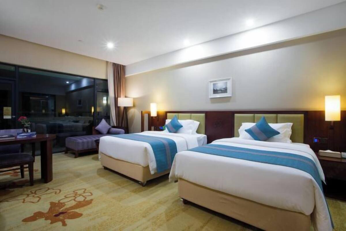 Habitación de hotel con dos camas, un escritorio y una ventana.