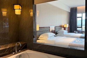 Une chambre d’hôtel dotée d’un grand miroir qui reflète le lit, une baignoire et une coiffeuse avec un lavabo.