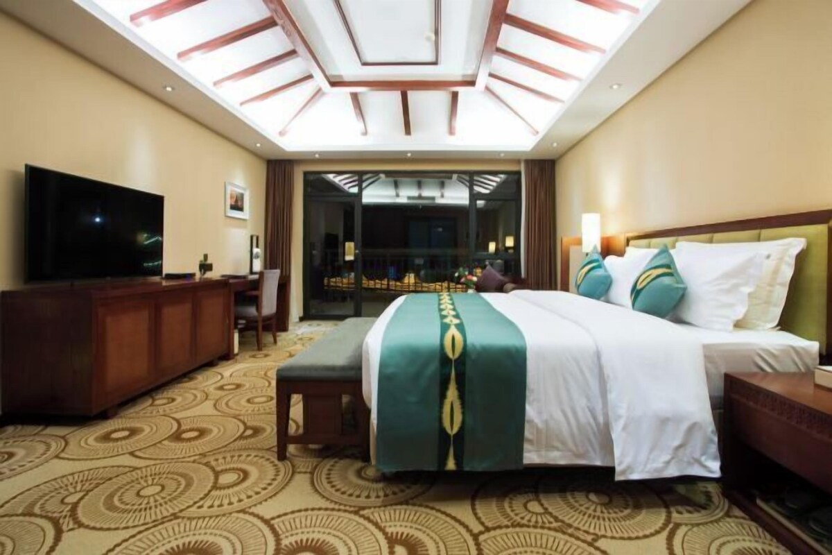 Een hotelkamer met een groot bed, een televisie, een bureau en een kamerbreed tapijt met dessin.