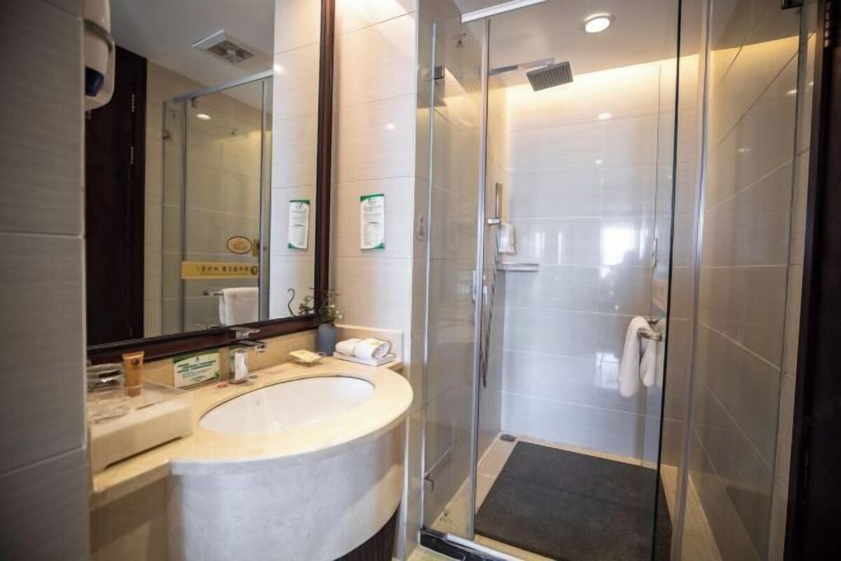Een moderne badkamer met een glazen douchecabine, een wastafel met spiegel en een handdoekrek.