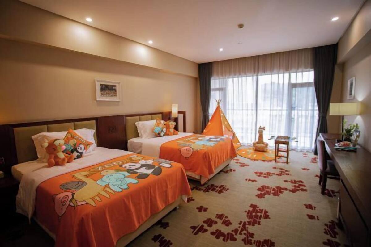 Habitación de hotel con dos camas, un escritorio, una silla y una ventana con cortinas.