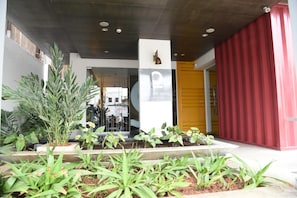 A hotel entrance with a modern design, a signboard, and a red door.
