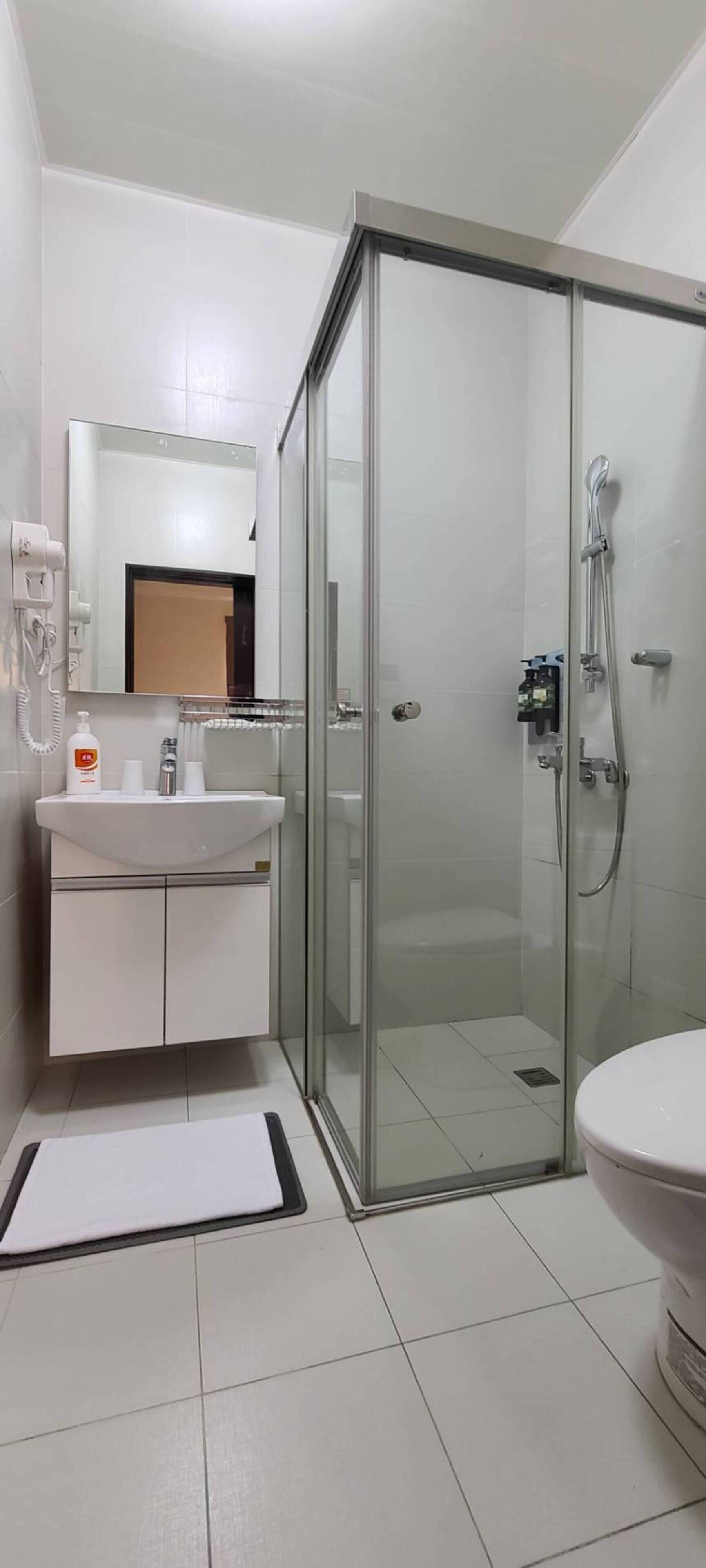 A modern bathroom with a glass-enclosed shower, a white sink, and a toilet.