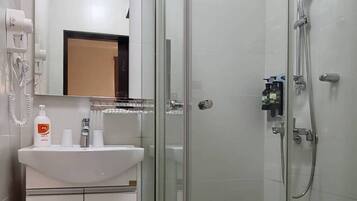 A modern bathroom with a glass-enclosed shower, a white sink, and a toilet.