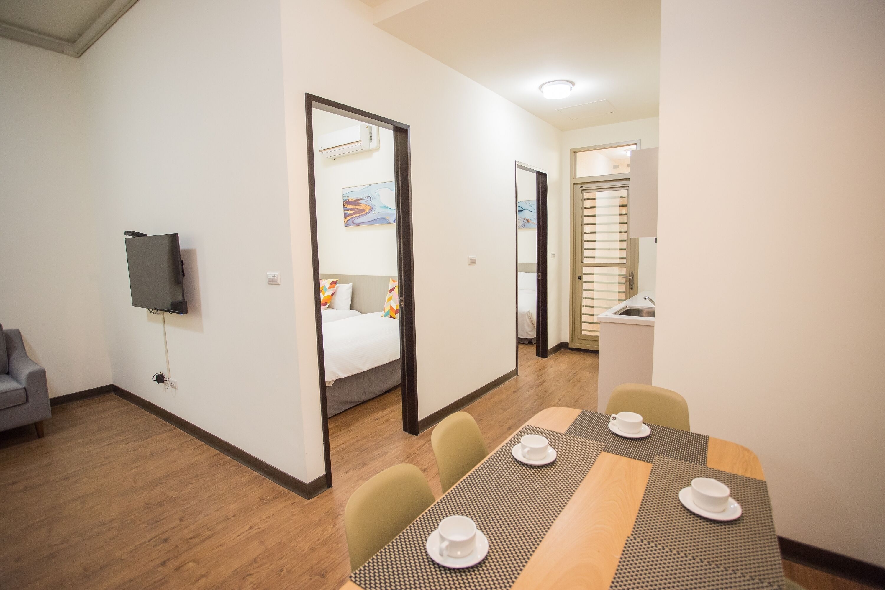 Une chambre d’hôtel comprenant un lit, une télévision, une table à manger avec des chaises et une kitchenette.