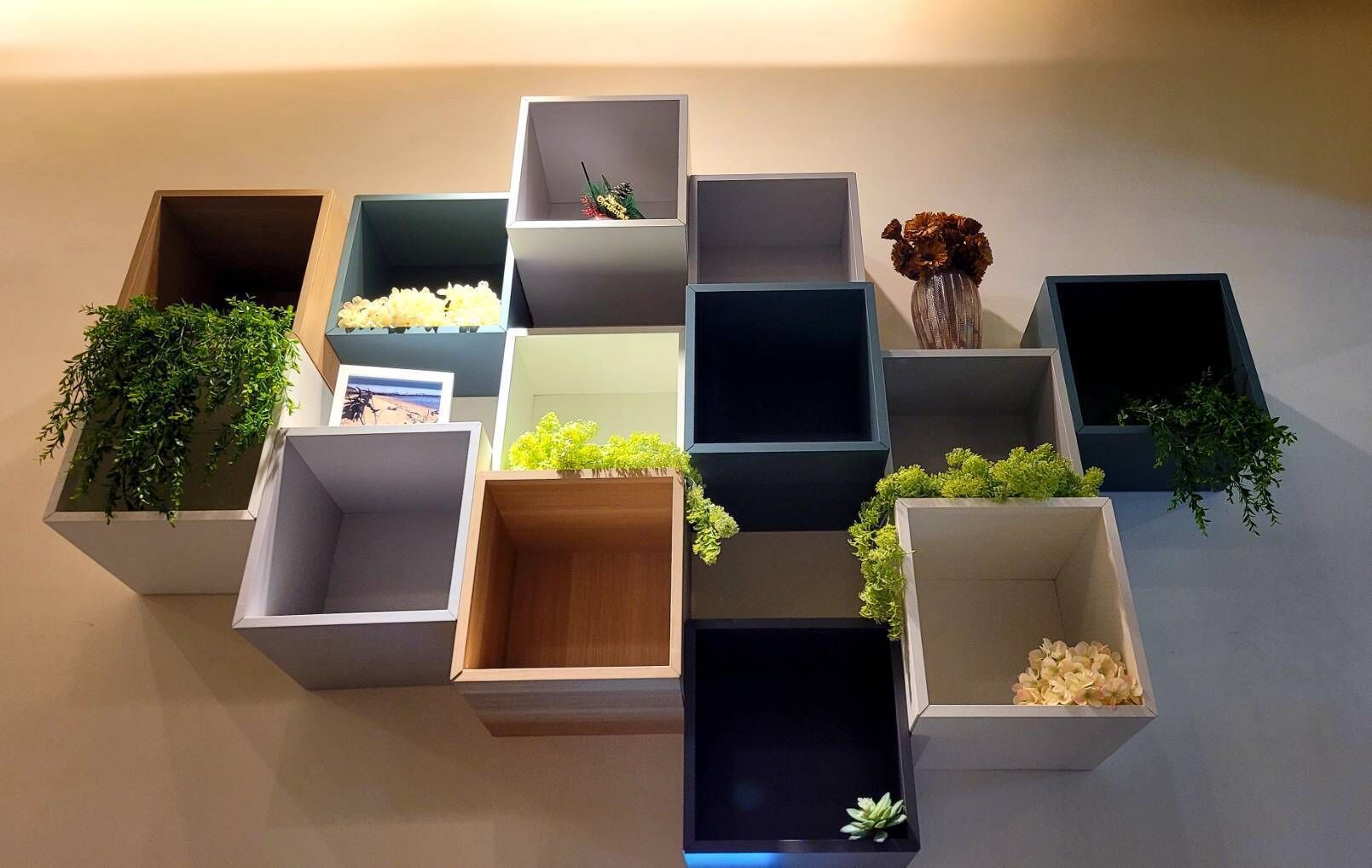 Un mueble de pared con varios compartimentos, algunos con plantas y otros vacíos.