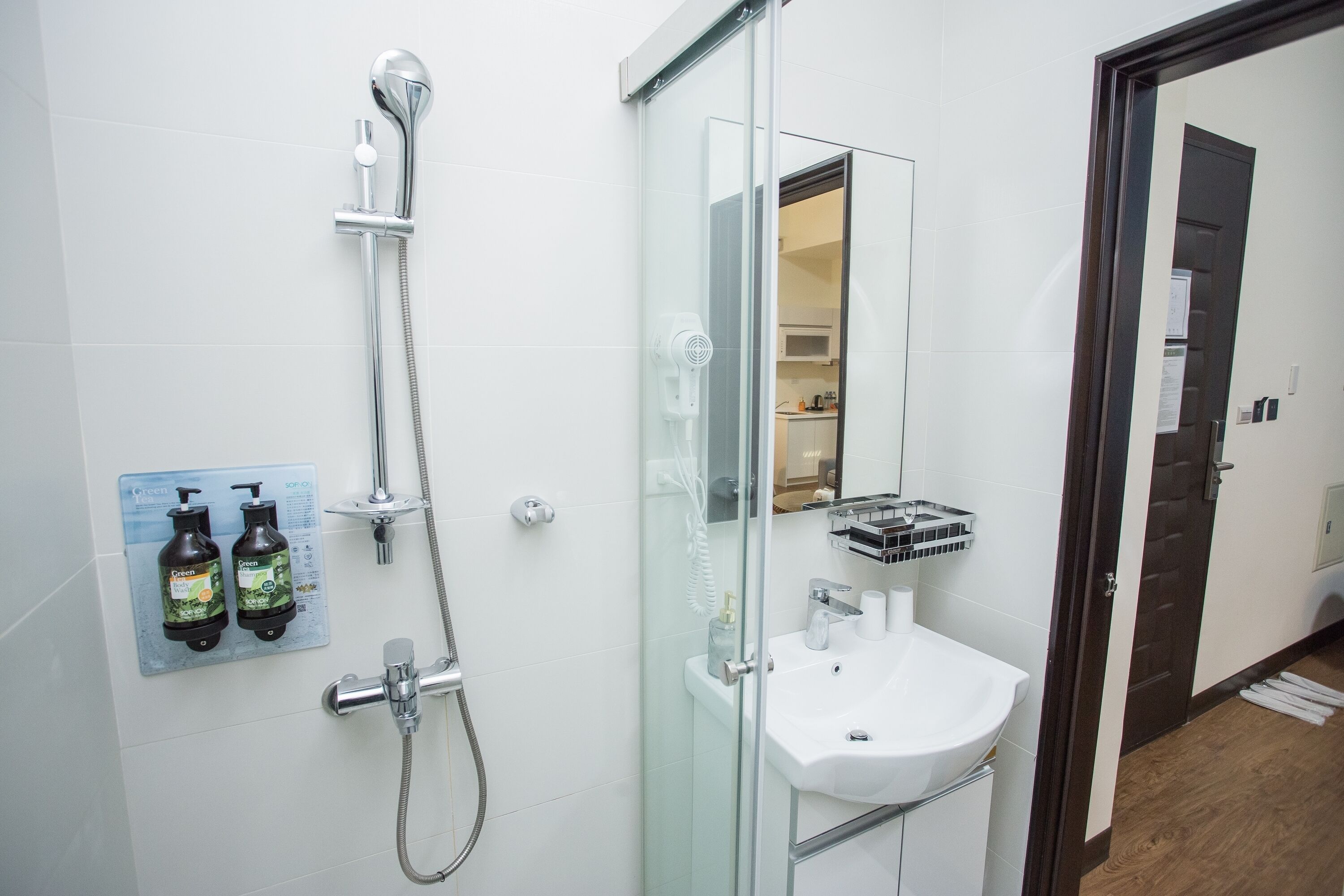Un baño moderno con cabina de ducha de vidrio, un lavamanos blanco y un espejo.