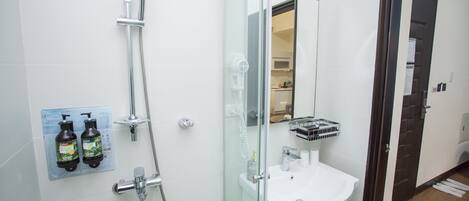 Un baño moderno con cabina de ducha de vidrio, un lavamanos blanco y un espejo.