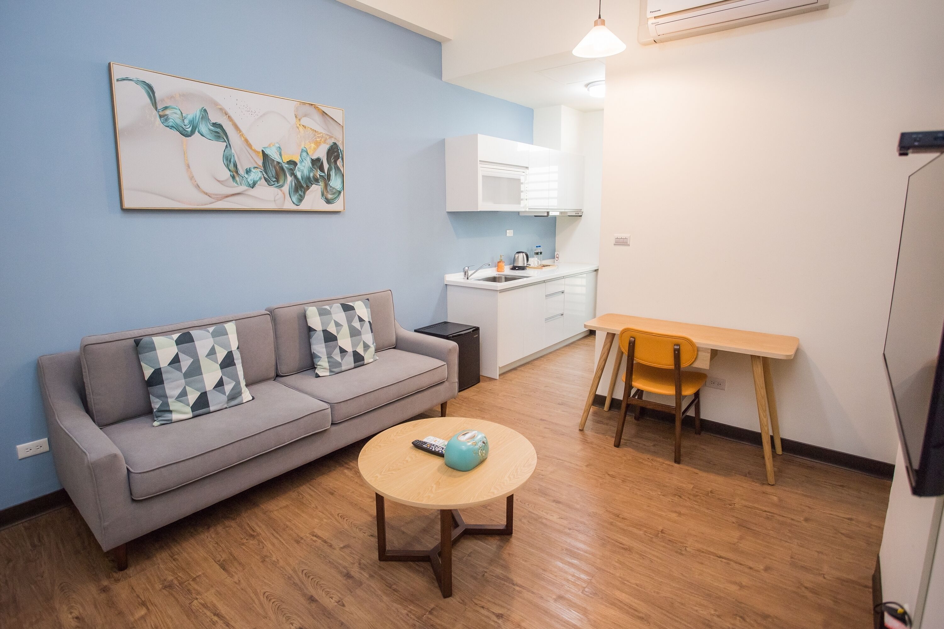 A modern living room with a grey sofa, a round coffee table, and a painting on the wall.