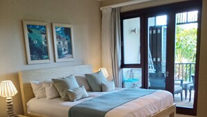 A bedroom with a bed, nightstands, a ceiling fan, and a view of the outside balcony.