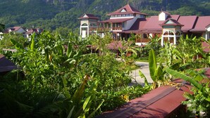 A resort with multiple buildings, lush greenery, and mountainous terrain in the background.