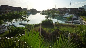 A marina with boats docked, surrounded by greenery and buildings.