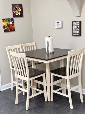 Un espace repas comprenant une table et quatre chaises, un distributeur d’essuie-tout et des œuvres d’art murales.