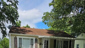 A single-story house with a front porch, a small front yard, and a white picket fence.
