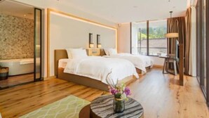 Una habitación de hotel moderna con una cama grande, un pequeño rincón de descanso y vistas al exterior.
