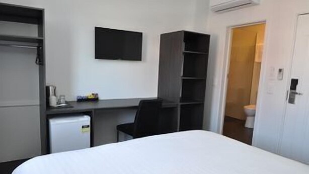 Hotellihuone, jossa on sänky, työpöytä, tuoli, televisio ja vaatekaappi.