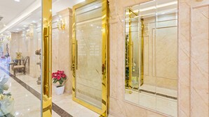 A hotel lobby with marble flooring, a reception desk, and a large mirror.