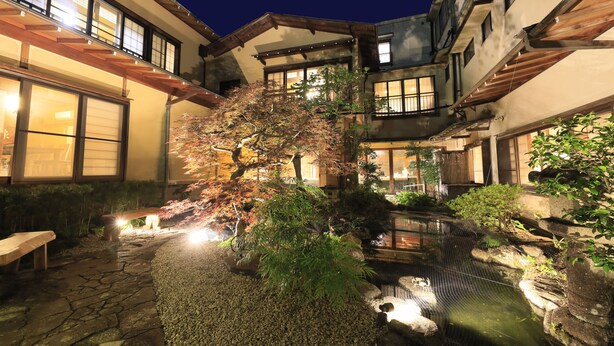 A traditional Japanese-style courtyard with a koi pond, stone pathways, and wooden benches. - Yugarawa Fuga (Yugawara)