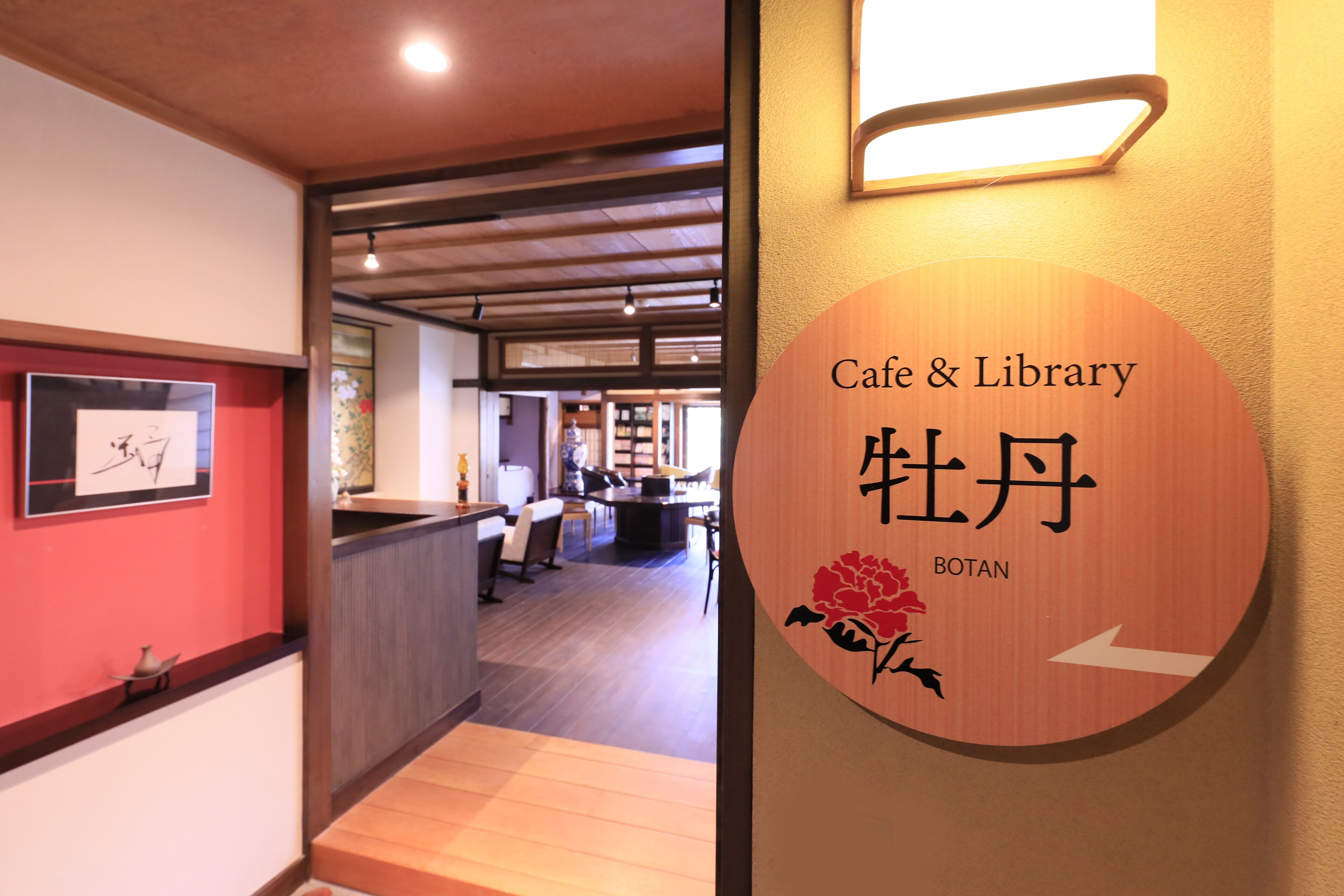 Schild für ein Café und eine Bibliothek mit japanischen Schriftzeichen und einer Rosenillustration.