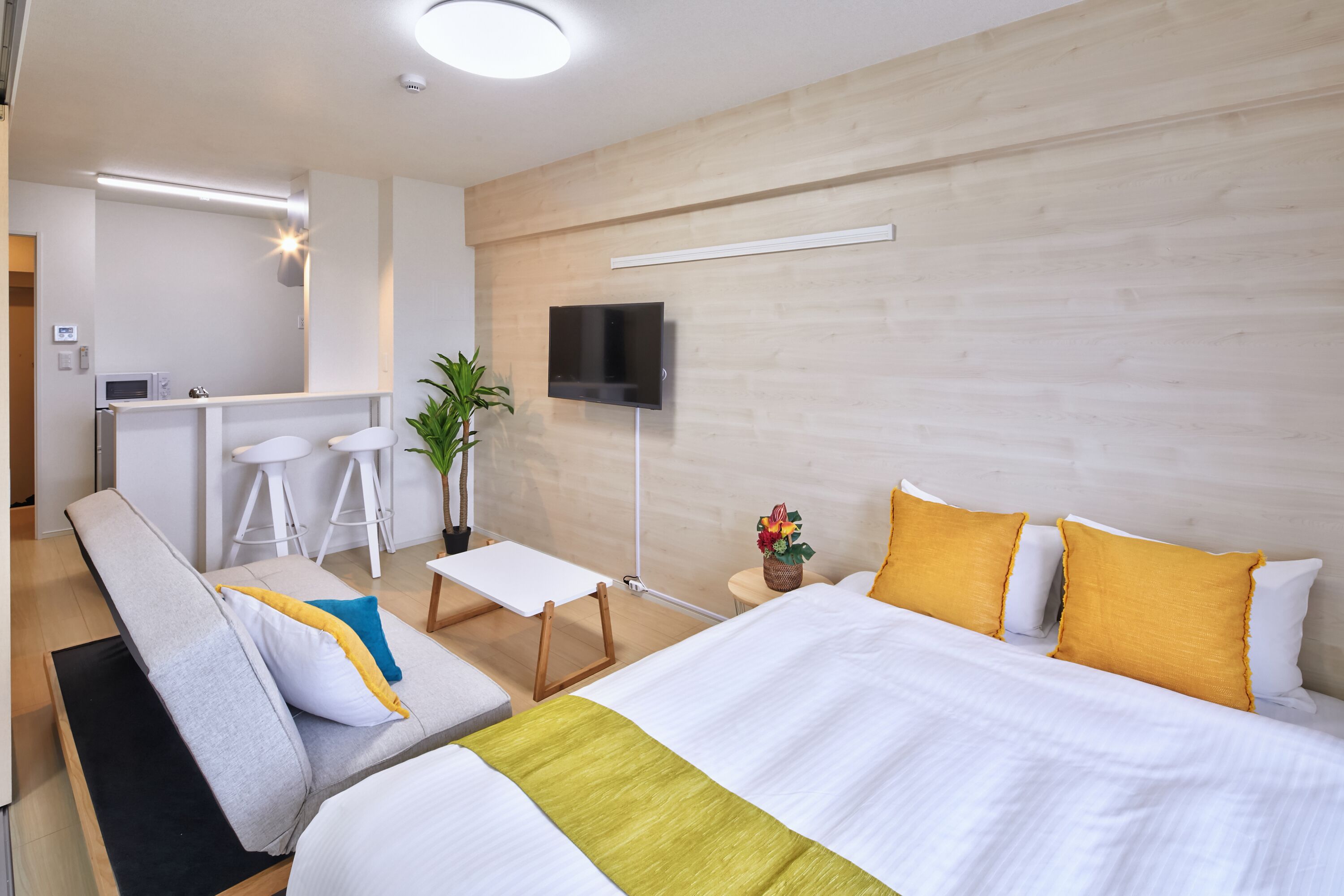 Ein Hotelzimmer mit Bett, Sofa, kleinem Tisch, Fernseher und einer Küchenzeile.