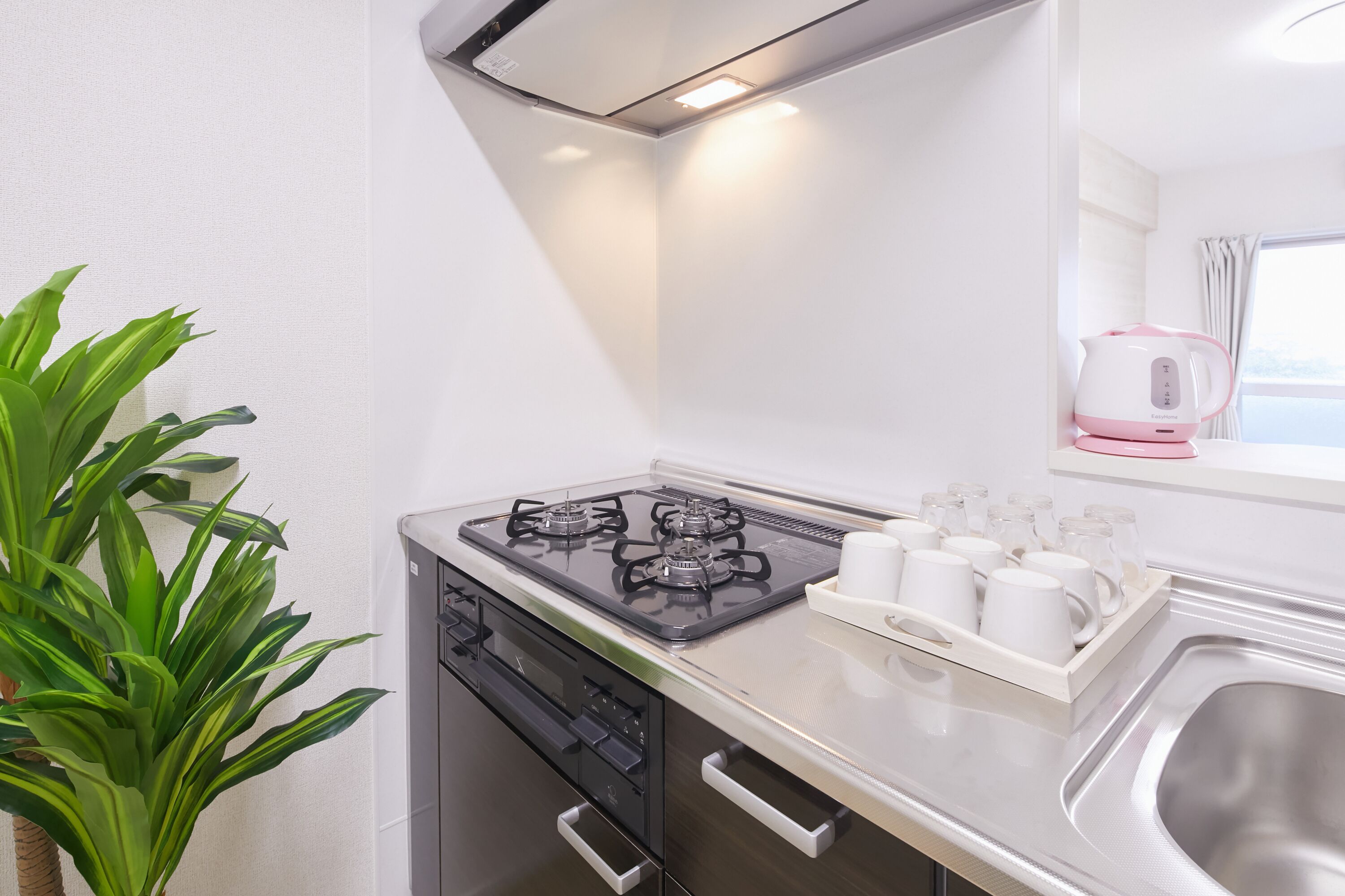 A modern kitchen with a gas stove, a sink, and a kettle on the countertop.