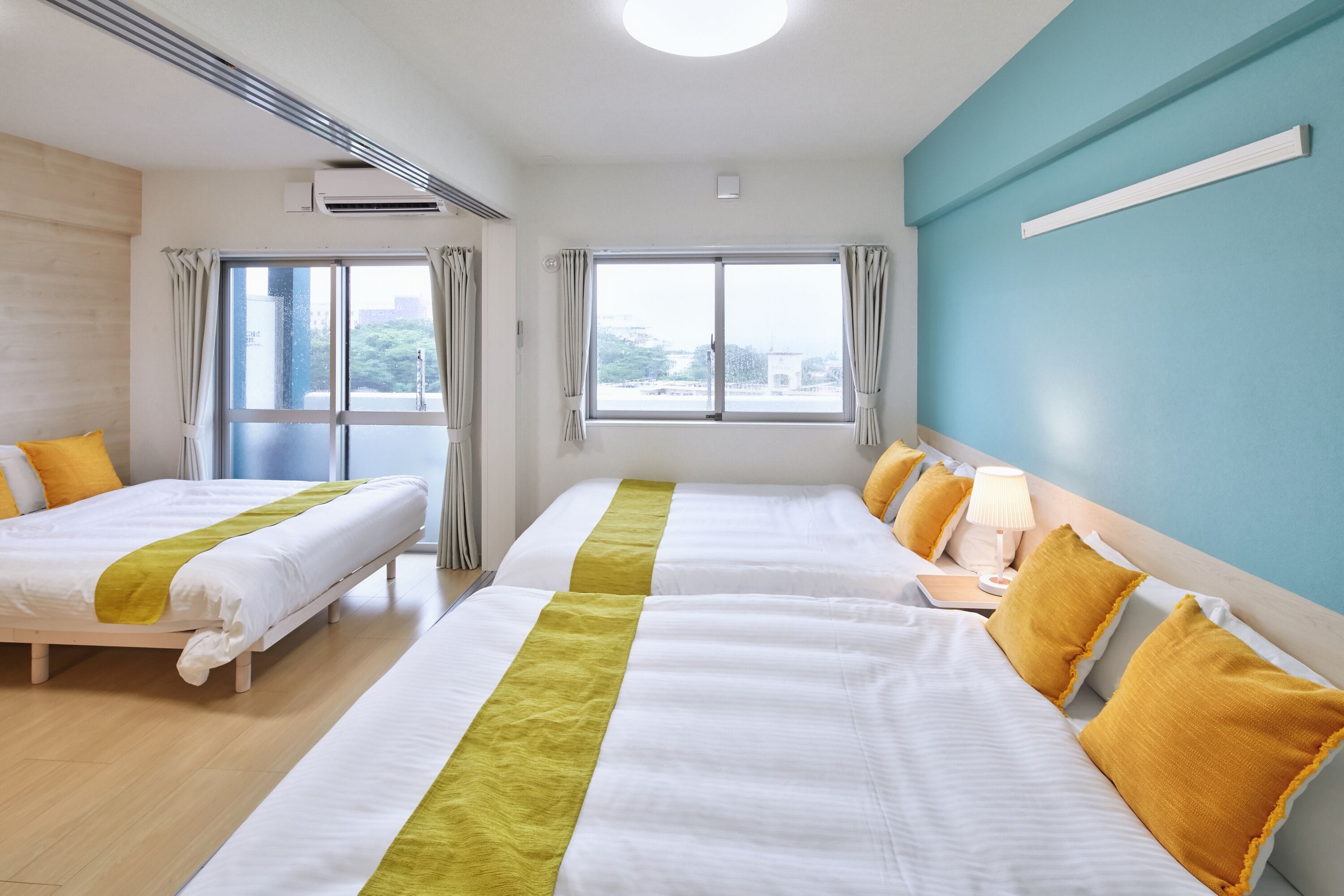 Een hotelkamer met twee bedden, een raam en een blauwe muur.