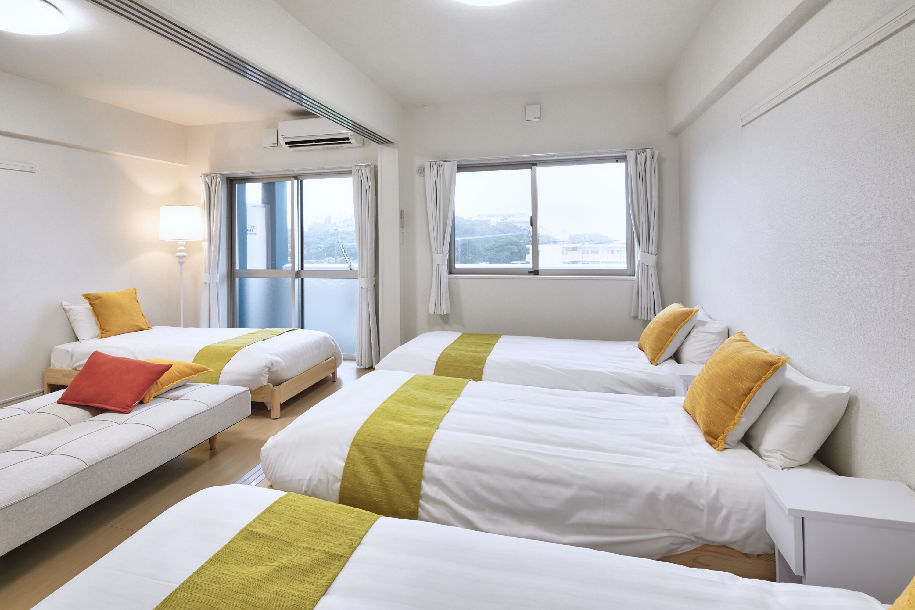 Habitación de hotel con dos camas, un sofá y una ventana con cortinas.