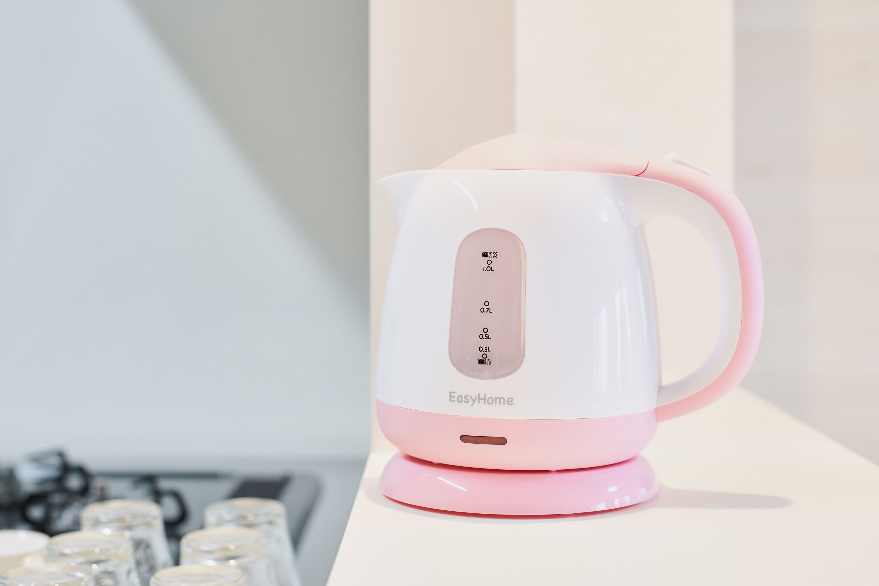 A pink and white electric kettle with a digital display, placed on a white surface.