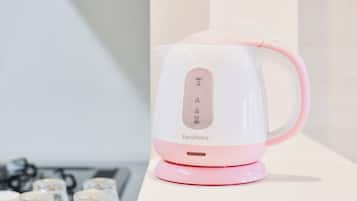 A pink and white electric kettle with a digital display, placed on a white surface.