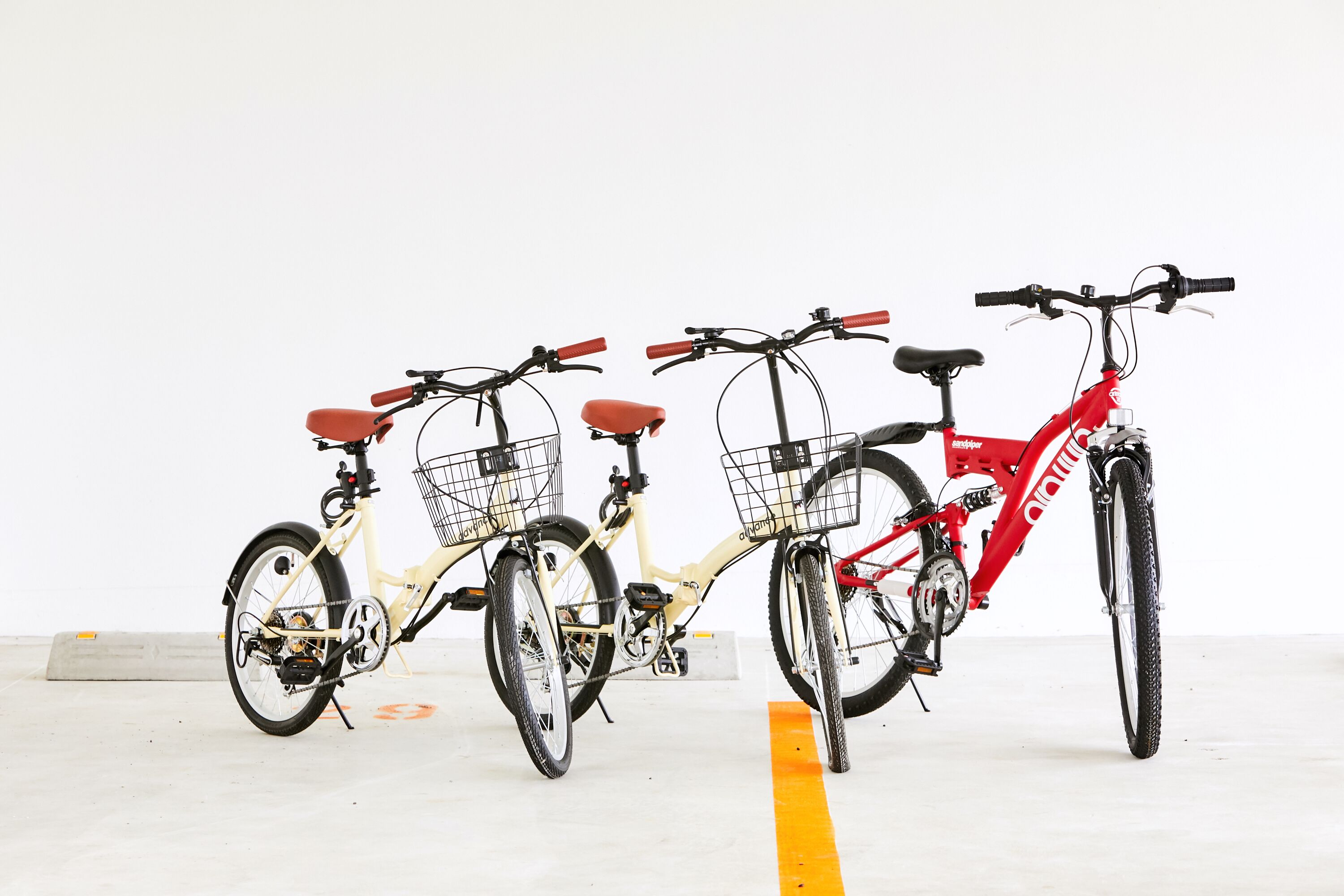 Three bicycles parked in a row, each with a basket and a seat.