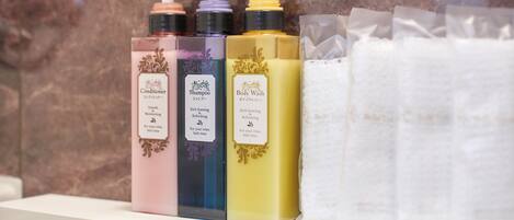 A shelf with bottles of conditioner, shampoo, and body wash, and a roll of white towels.