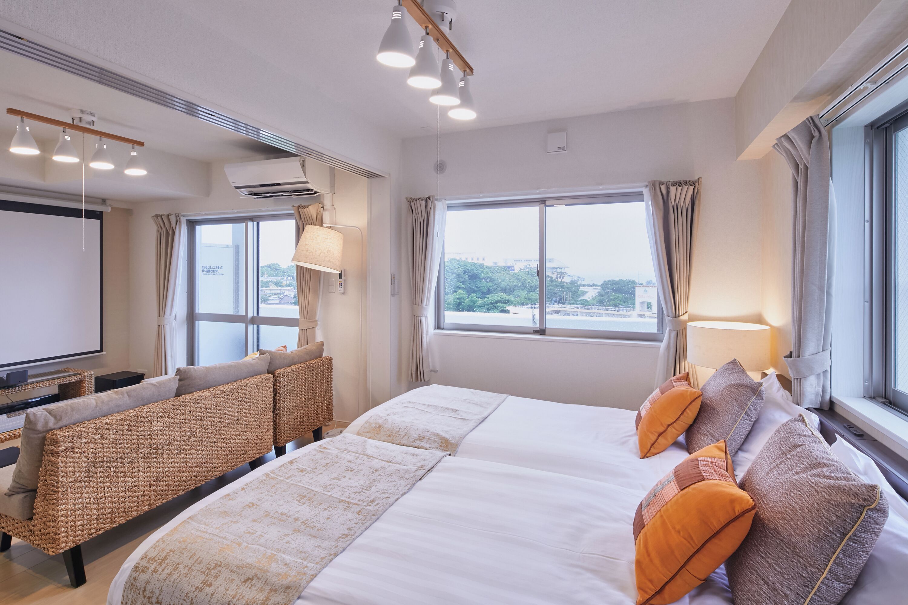 A hotel room with a large bed, a sofa, a TV, and a window with a city view.
