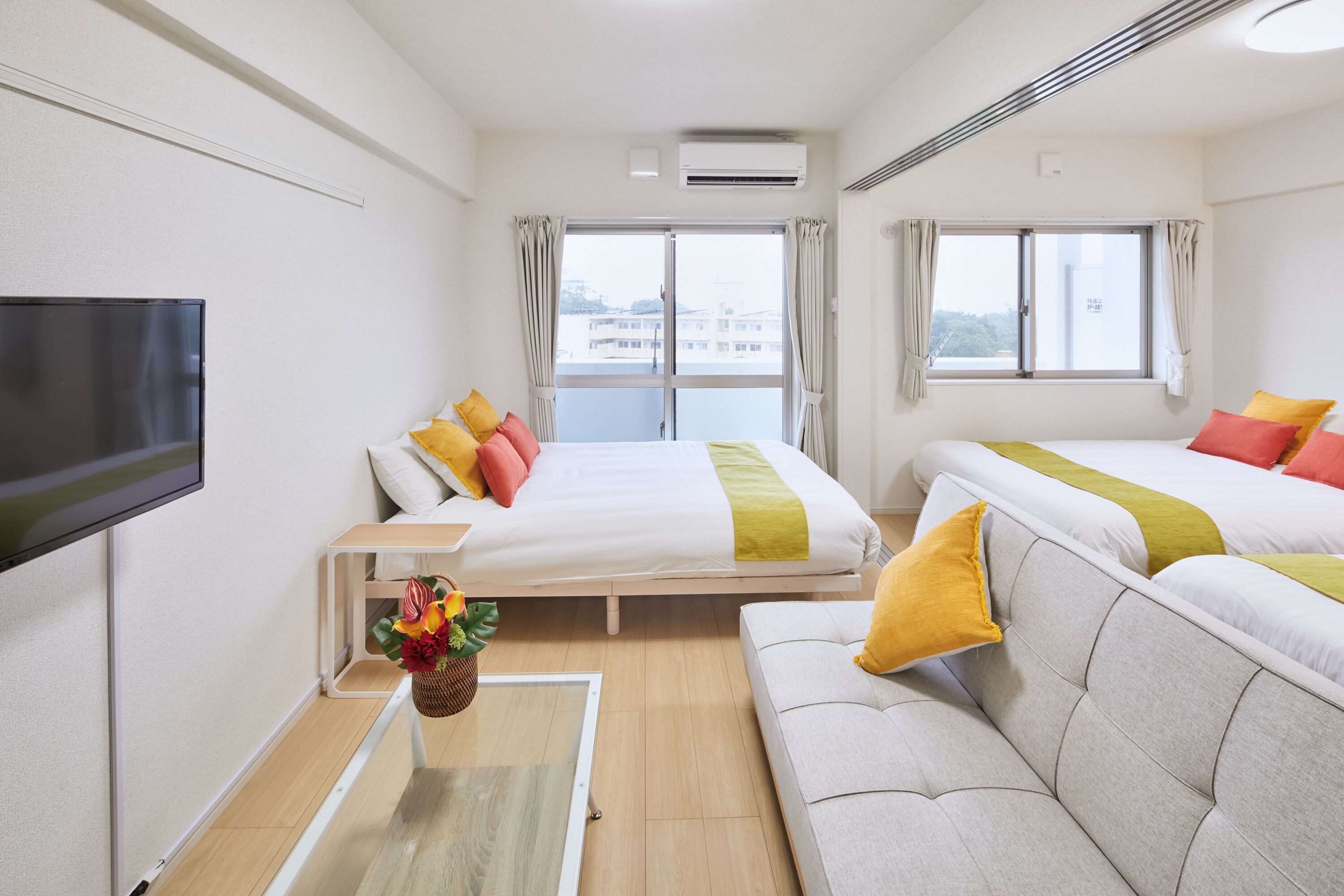 Hotellihuone, jossa on sänky, sohva, televisio ja ikkuna, jossa on verhot.