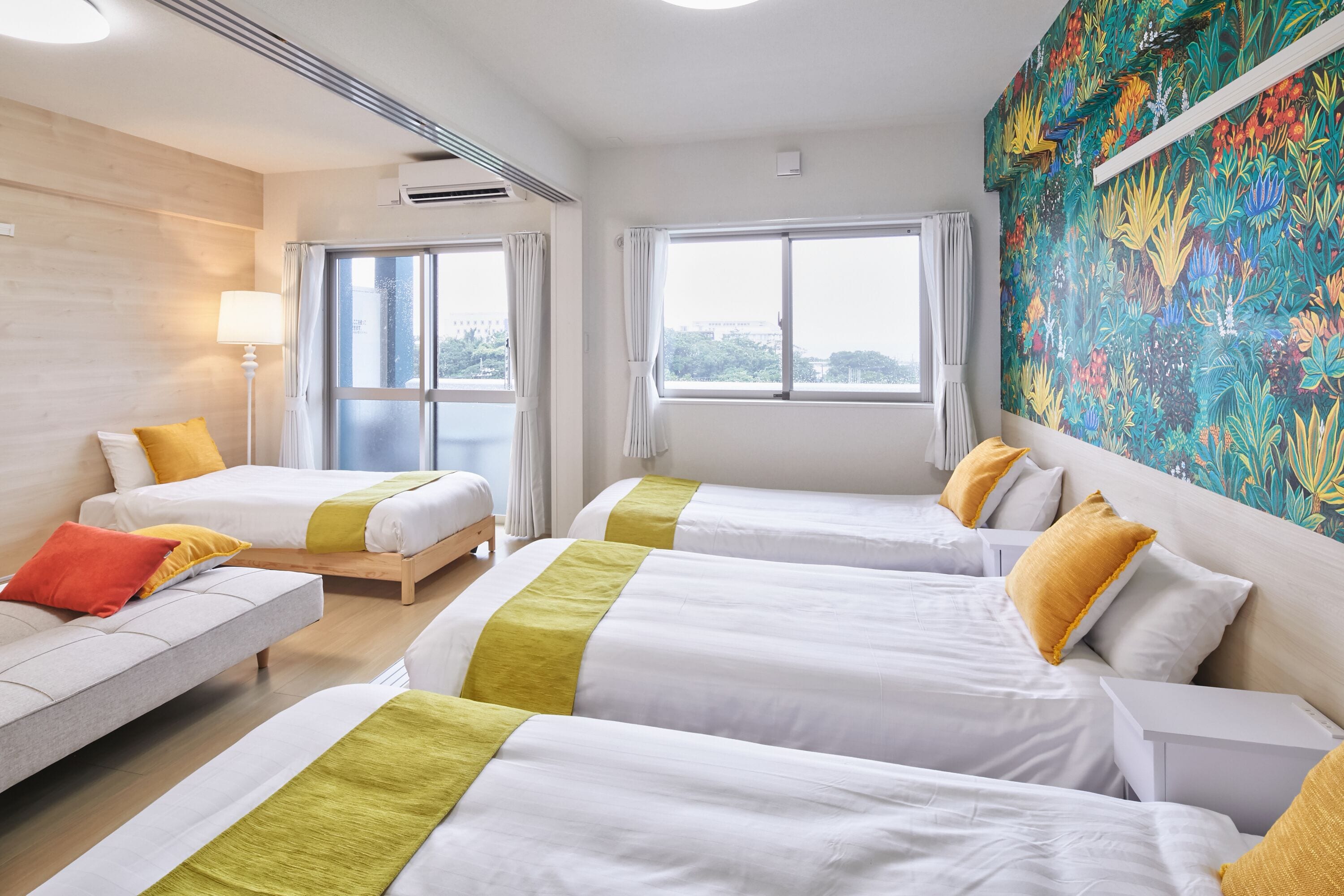 Habitación de hotel con dos camas, un sofá y un ventanal grande.