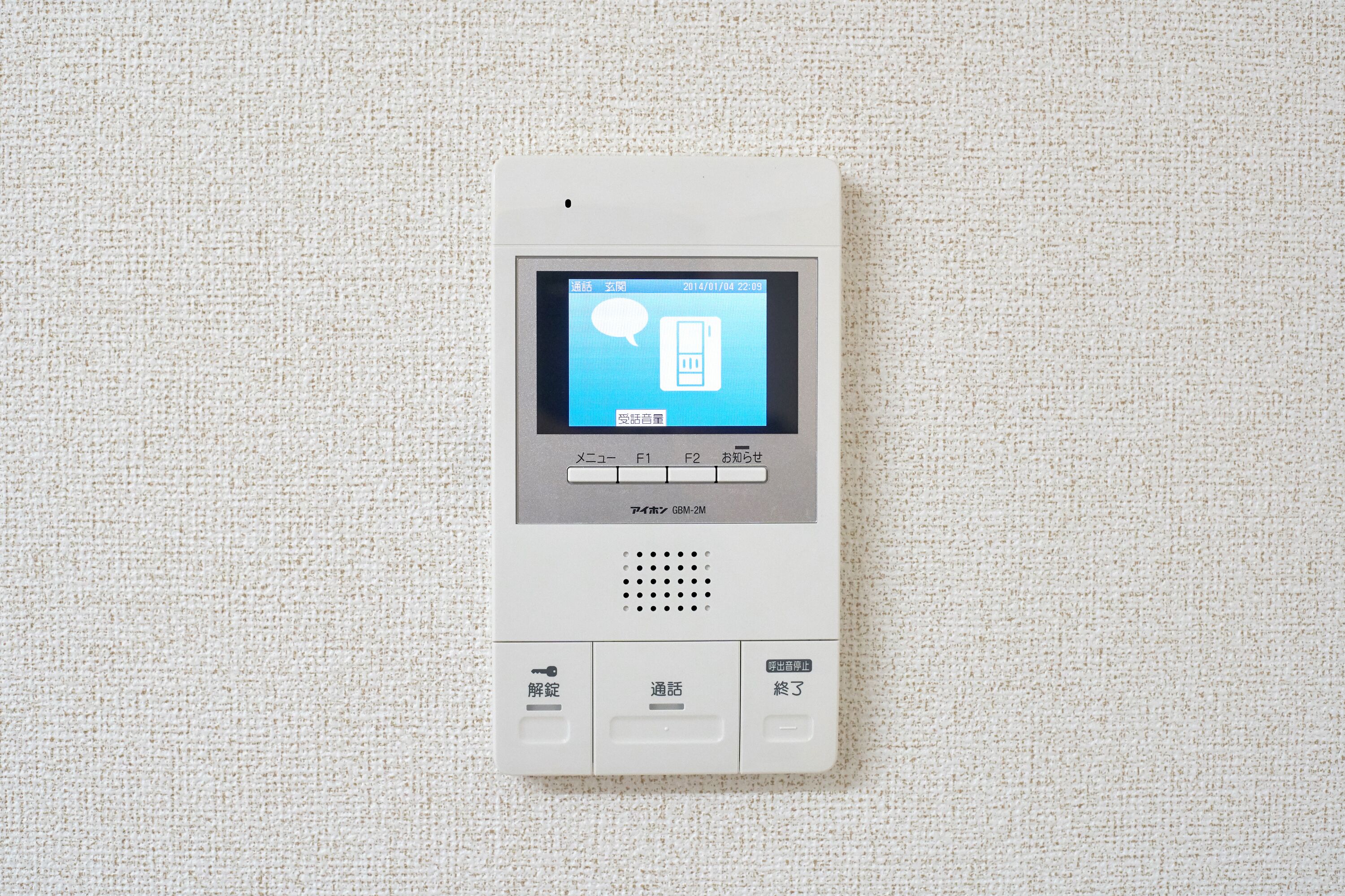A white intercom system with a digital display, buttons, and a speaker grille.
