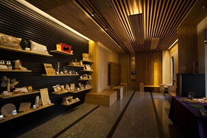 Un interior moderno con listones de madera en el techo, estanterías con diversos objetos y un banco a lo largo del pasillo.