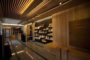 Un interior moderno con paneles de madera, un mostrador de recepción y estanterías con diversos objetos.