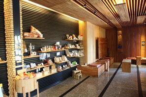 A modern interior with wooden shelves displaying various products, a seating area with benches, and a sloped ceiling with wooden panels. - Cypress House (Ji'an)