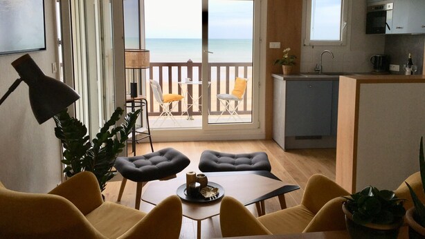 En moderne lejlighed med balkon med udsigt over havet, spiseplads og et kompakt køkken.