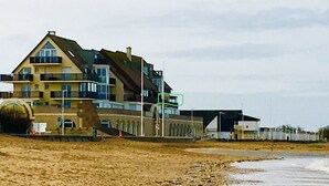 En bygning med flere etager og altaner, beliggende i nærheden af en strand.
