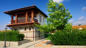 A two-story building with a balcony, stone facade, and a well-maintained garden. - Generaator House (Pomorie)