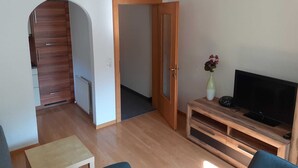 Una sala de estar con un mueble bajo de madera para el televisor, un televisor de pantalla plana y una mesita.