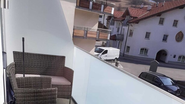 Un balcón con mobiliario de mimbre y vista a la calle.
