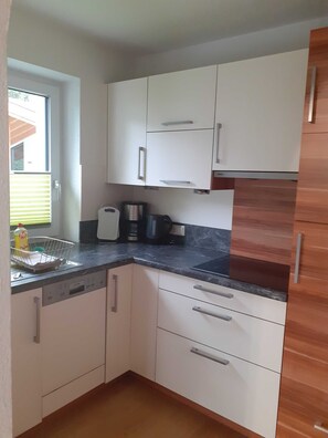 A compact kitchen with white cabinets, a black countertop, and a coffee maker.