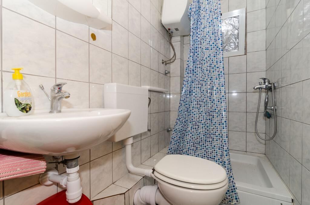 A bathroom with a white sink, a toilet, and a shower area.